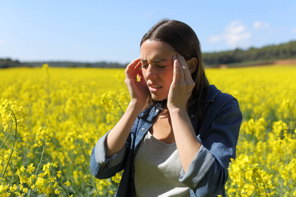 Stressed woman suffering head ache in a yellow field on summer - Valokuva, kuva
