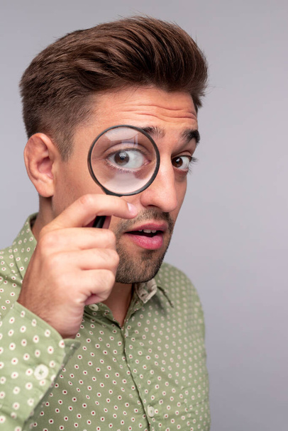 Curious man with magnifier looking at camera - Photo, Image