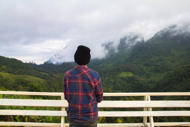 Hombre joven asiático en camisa escocesa y sombrero negro senderismo en la cima de la montaña por encima de las nubes y la niebla Hiker al aire libre. Doi Luang Chiang Dao Chiangmai Provincia, Por la mañana. - Foto, imagen