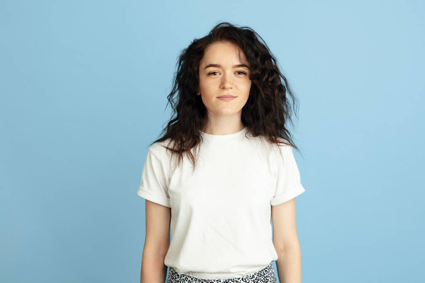 Portrait of young beautiful curly caucasian woman isolated over light blue studio background. - Photo, Image