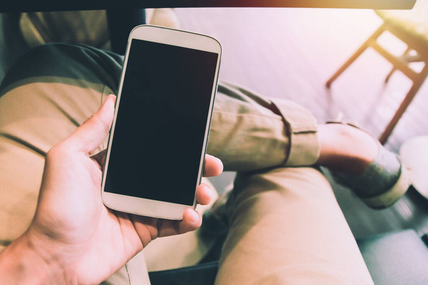 Primo piano di uomini mani in mano toccando telefono cellulare con spazio vuoto copia per il vostro messaggio di testo in caffè con luce tramonto, tono Vintage. - Foto, immagini