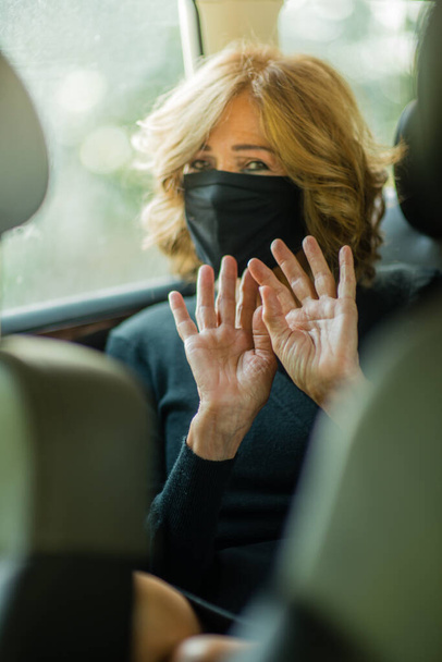 An elegant elderly woman wearing a face mask and refusing to take pictures on the car - Photo, image