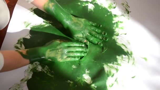 Nő kenet rajzol zöld festék egy fehér felületen. - Felvétel, videó