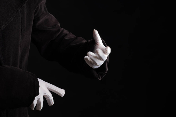 Hand gestures. Showman or magician illusionist in white gloves on a black background. - Foto, afbeelding