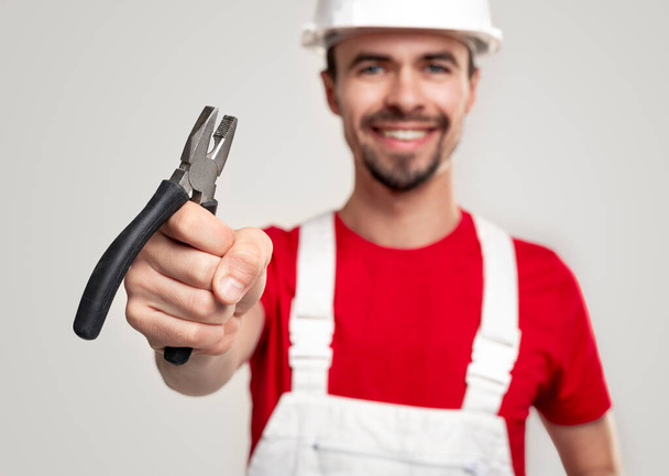 Cheerful male builder showing pliers - Foto, Imagen