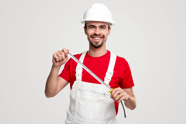 Cheerful handyman with measuring tape - Foto, afbeelding