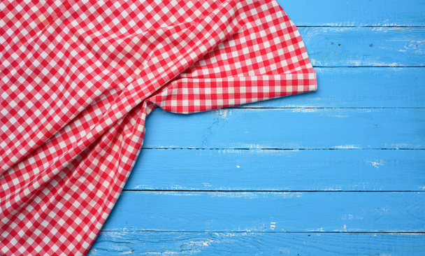 servilleta de cocina plegada de algodón rojo y blanco sobre un fondo azul de madera, vista superior, espacio para copiar - Foto, Imagen
