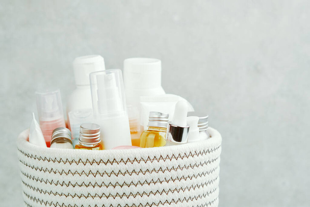Textile white basket and many different cosmetic bottles, tubes, jars. Skin care, spa treatments. - Photo, Image