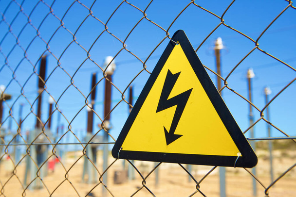 Σήμανση ηλεκτρικού κινδύνου τοποθετημένη σε μεταλλικό φράκτη. - Φωτογραφία, εικόνα