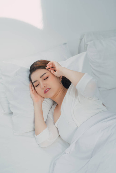 Kranke Asiatin mit Erkältung schläft zu Hause mit hohem Fieber und Schlaflosigkeit im Bett - Foto, Bild