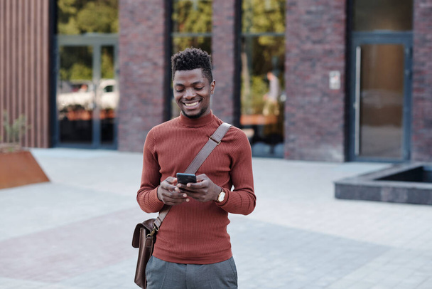 Happy young businessman of African ethnicity using smartphone - Foto, Imagem