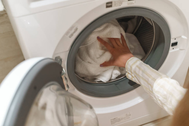 Дівчина-підліток завантажує одяг у пральну машину
. - Фото, зображення