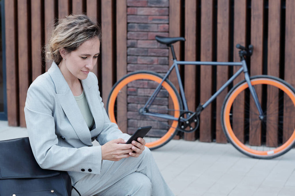 Молода бізнес-леді смс в смартфоні на відкритому повітрі
 - Фото, зображення