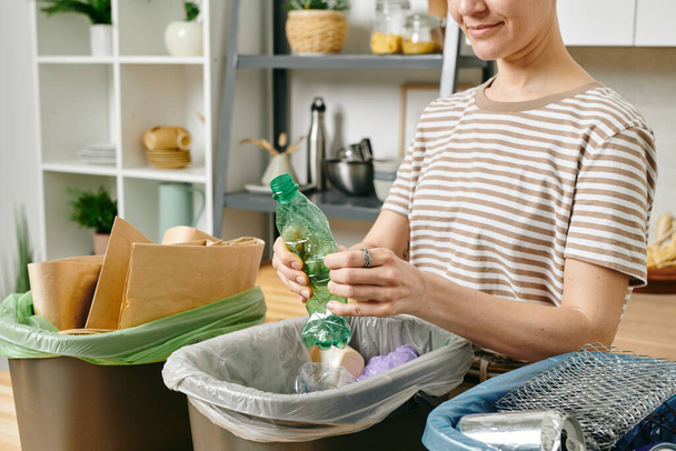 Mladá žena rozbíjet plastové láhve přes odpadkový koš - Fotografie, Obrázek