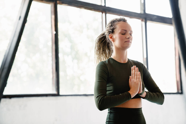 Young sportswoman meditating during yoga practice indoors - Foto, Imagem