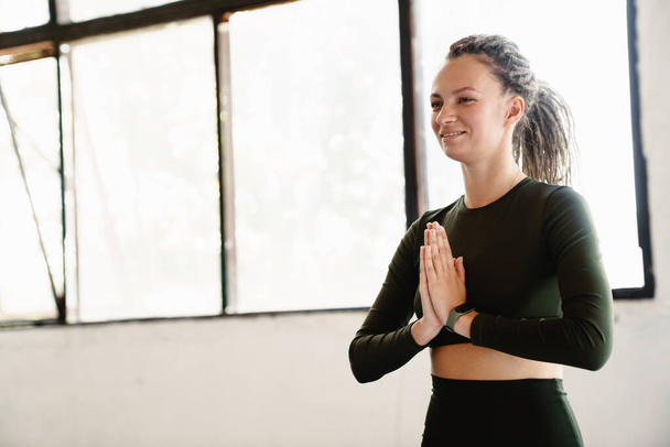 Young sportswoman meditating during yoga practice indoors - Photo, image