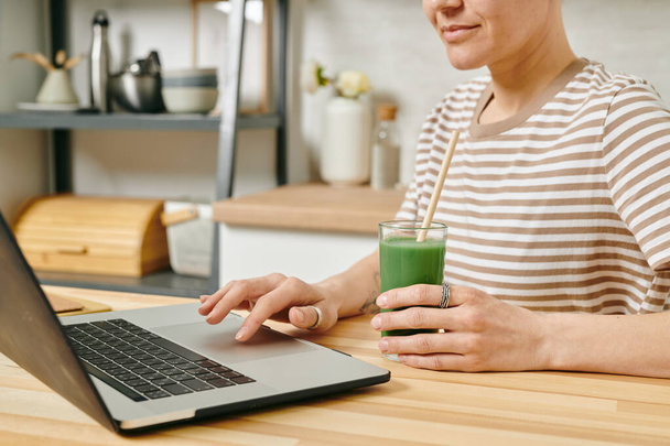 Сучасна жінка з напоєм сидить перед ноутбуком
 - Фото, зображення