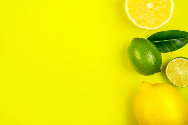 Bright summer citrus flatlay with lemons and limes isolated on yellow background. - Foto, afbeelding