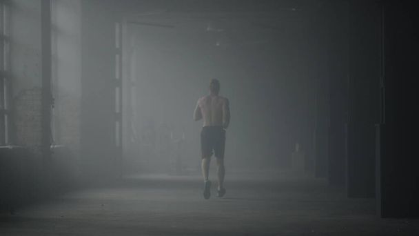 Muscular man doing cardio workout in loft building. Guy running in corridor - 写真・画像