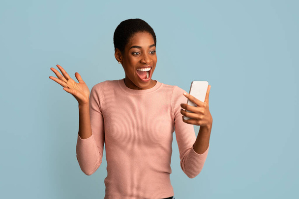 Mobilní nabídka. Nadšený africký americký dáma při pohledu na Smartphone obrazovky v ruce - Fotografie, Obrázek