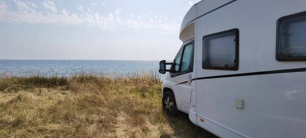 Yazın deniz kenarında bir karavan. Kumsal ağaçları. Mavi gökyüzü tatillerde seyahat ediyor. - Fotoğraf, Görsel