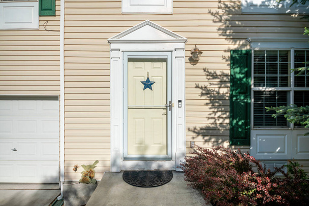 Außenseite einer Haustür mit blauem Stern, Türklingel, Vinyl-Seitenwänden und Fenstern - Foto, Bild