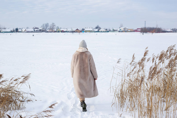 Fiatal lány bézs ruhában, szőrme kabát mesterséges szőrméből séta télen - Fotó, kép