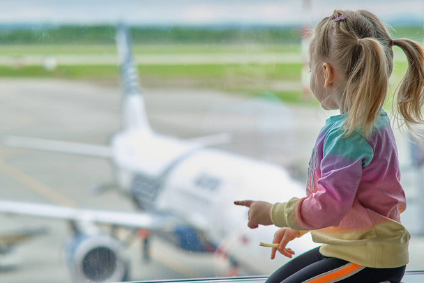 Khabarovsk, Rusia - 25 de mayo de 2021: una niña en el aeropuerto mira los aviones. - Foto, imagen