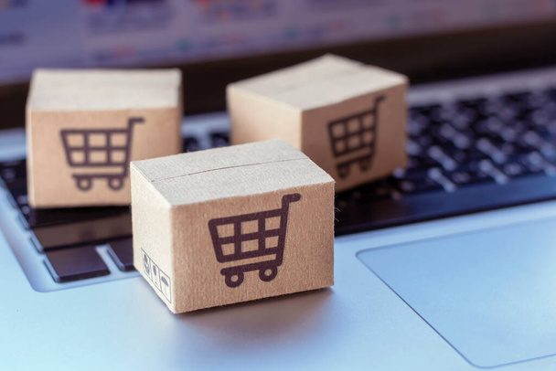 Online vásárlás. Kartondoboz egy bevásárlókosár logóval a laptop billentyűzetén. Bevásárlási szolgáltatás az interneten. házhozszállítás - Fotó, kép