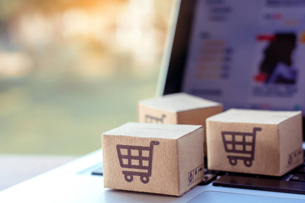 Online einkaufen. Karton mit einem Warenkorb-Logo auf der Laptop-Tastatur. Shopping-Service im Internet. bietet Lieferung nach Hause - Foto, Bild