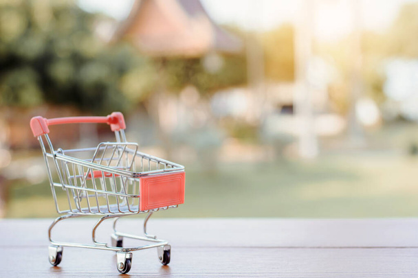 Koncepcja zakupów - pusty koszyk lub wózek na brązowym drewnianym stole. zakupy online konsumenci mogą robić zakupy w domu i usługi dostawy. z przestrzenią do kopiowania - Zdjęcie, obraz