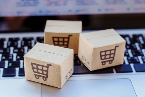 Online einkaufen. Karton mit einem Warenkorb-Logo auf der Laptop-Tastatur. Shopping-Service im Internet. bietet Lieferung nach Hause - Foto, Bild