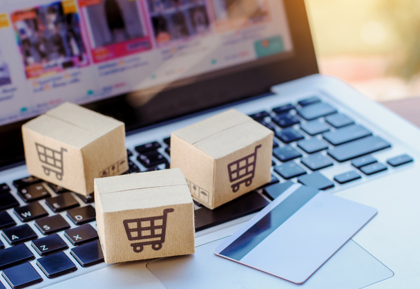 Online einkaufen. Kreditkarten- und Kartonschachtel mit einem Warenkorb-Logo auf der Laptop-Tastatur. Shopping-Service im Internet. bietet Hauszustellung - Foto, Bild