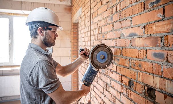 A professional builder in work clothes works with a cutting tool. - Photo, Image