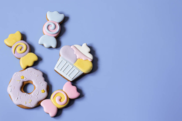 Flat lay of bright glazed gingerbread cookies on a blue background copy space. - Photo, Image