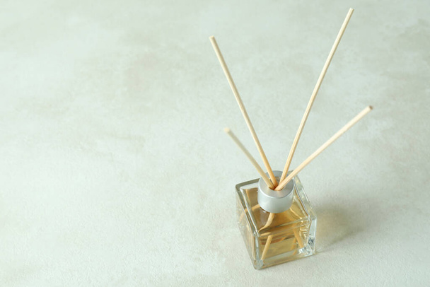 Diffuser bottle with sticks on white textured table - 写真・画像