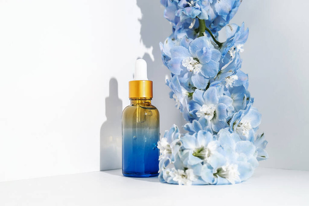 Cosmetic bottles and flowers on a white background. - Foto, Imagen