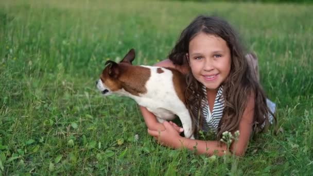 cute little caucasian sad girl embrace their dog lying on grass - Footage, Video