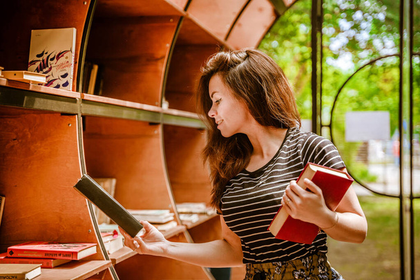 A beautiful young woman in the library holds books. Russian books. Togliatti, Russia - 29 May 2021 - Fotó, kép