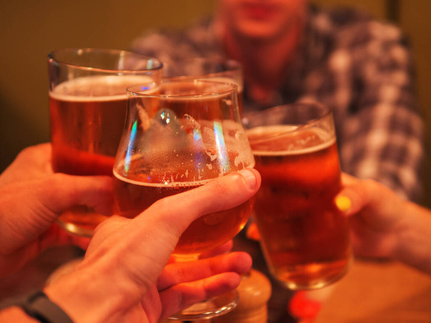 バーでビールを飲んでいる友人のグループ、クローズアップビールグラストースト - 写真・画像