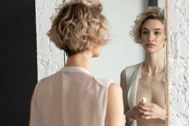 young beautiful woman paints lips near the mirror - Foto, Imagen