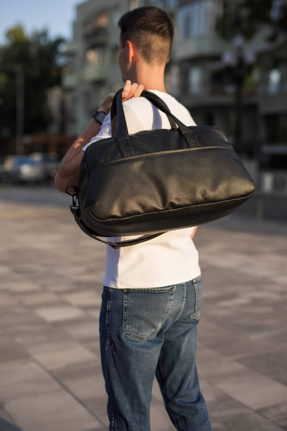 A man walks around a city holding bag on his shoulder - Foto, afbeelding
