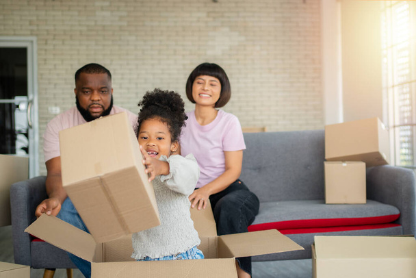 Mixed Race families are sitting on the sofa for rest after moving to a new house on the first day after buying real estate.  Concept of starting a new life for a new family. - Photo, Image