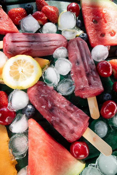 Photographic shot of popsicles made with red fruit on a table served with various fruit  - Valokuva, kuva
