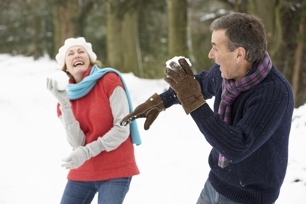 Senior Couple Having Snowball Fight In Snowy Woodland - Фото, зображення