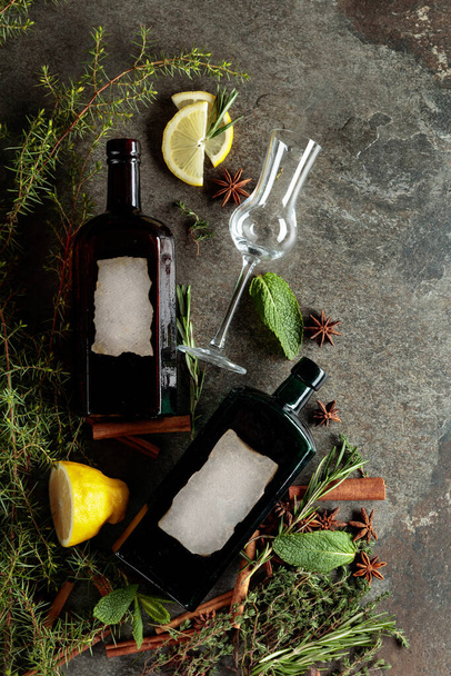 Botellas vintage de ginebra y varios ingredientes en una mesa de piedra vieja. Hay una etiqueta en blanco en las botellas. Vista superior. - Foto, Imagen