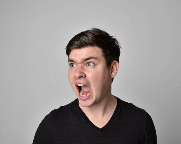 Close up head and shoulders portrait of a brunette. young man with a variety of expressive facial expressions. Isolated on a light grey studio background. - Photo, image