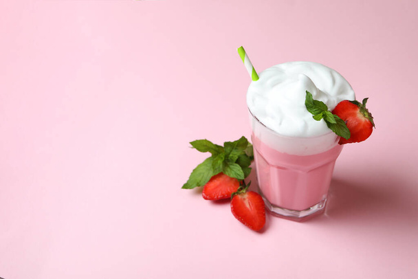 Glass of strawberry milkshake and ingredients on pink background - Фото, изображение