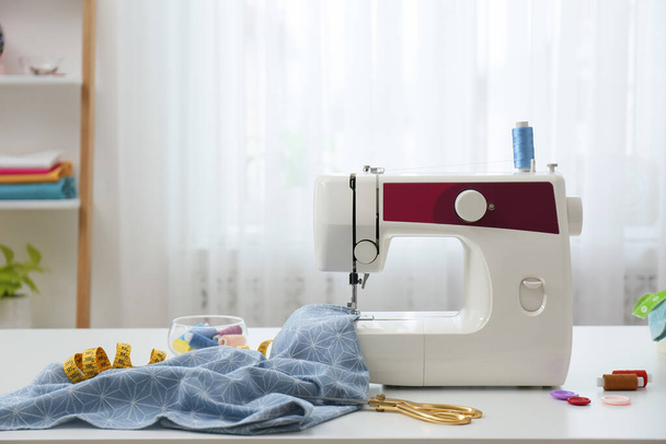 Modern sewing machine, fabric and accessories on table indoors, space for text - Foto, immagini