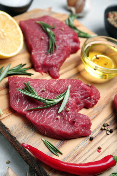 Fresh raw meat steaks and spices on wooden board, closeup - Foto, imagen